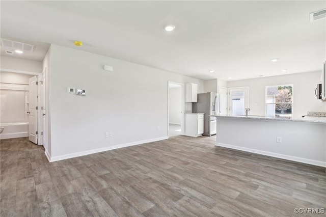 unfurnished living room with baseboards, wood finished floors, visible vents, and recessed lighting