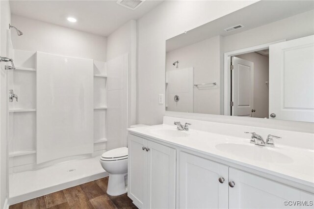 full bath with wood finished floors, a sink, visible vents, and a stall shower