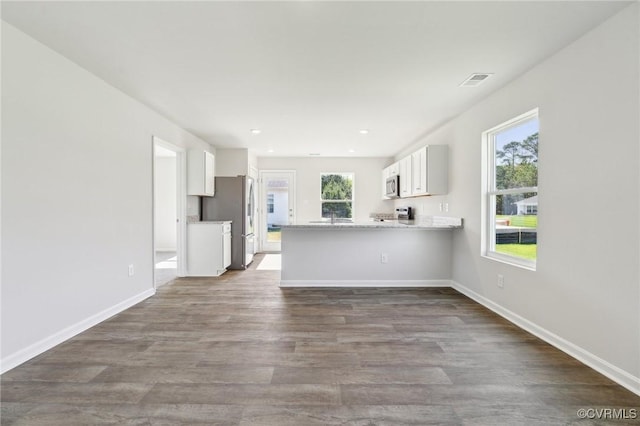 unfurnished living room with a sink, dark wood finished floors, baseboards, visible vents, and recessed lighting