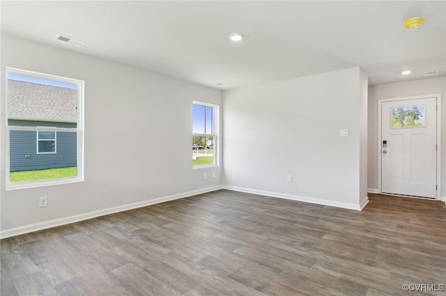unfurnished room with wood finished floors, visible vents, and baseboards