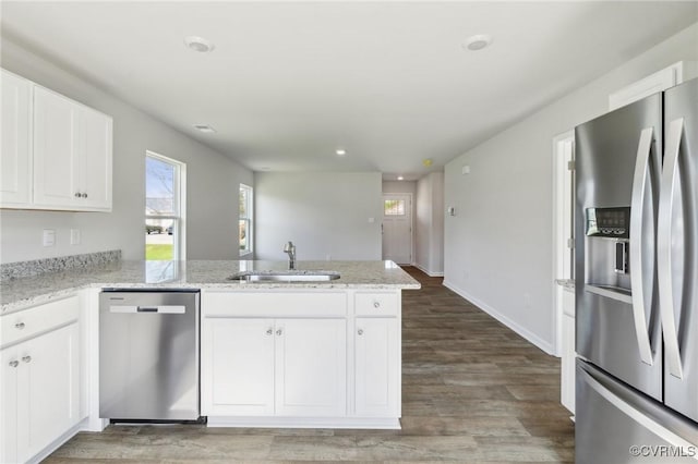 kitchen with white cabinets, a peninsula, appliances with stainless steel finishes, and a sink