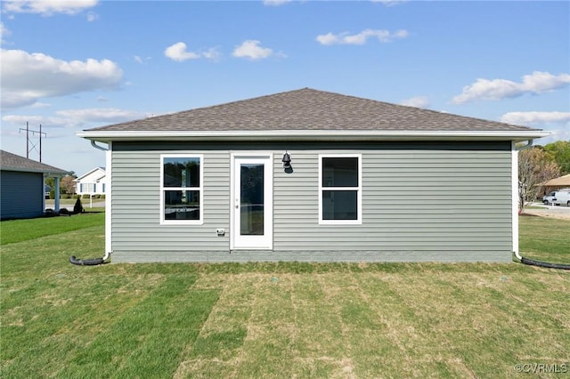 rear view of property featuring a lawn and a shingled roof
