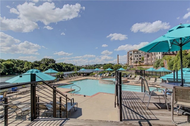 community pool with fence, a hot tub, and a patio