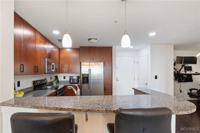 kitchen featuring a kitchen breakfast bar, dark stone countertops, brown cabinets, a peninsula, and appliances with stainless steel finishes