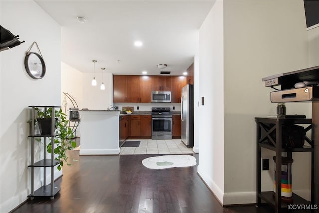 kitchen featuring brown cabinetry, pendant lighting, stainless steel appliances, light wood-style flooring, and baseboards