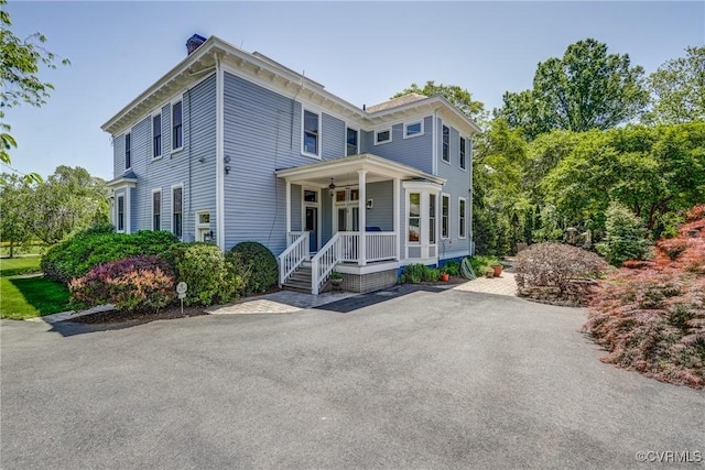 italianate home featuring a porch and a chimney