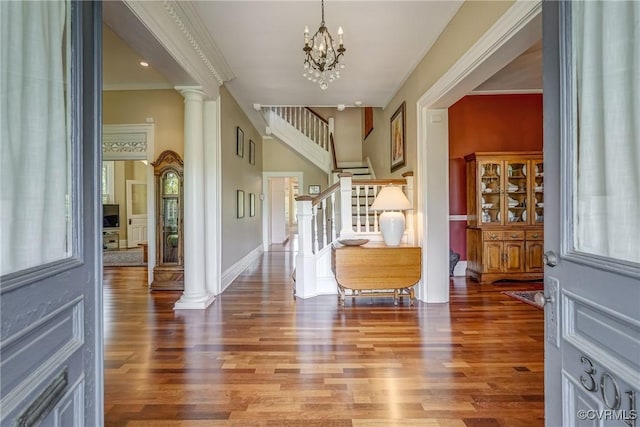 entrance foyer with a notable chandelier, wood finished floors, a wealth of natural light, and stairway