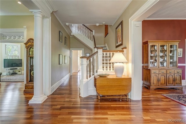 entryway featuring crown molding, ornate columns, wood finished floors, and stairway