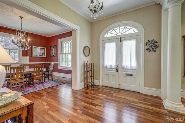 entryway featuring ornate columns, baseboards, a notable chandelier, and wood finished floors