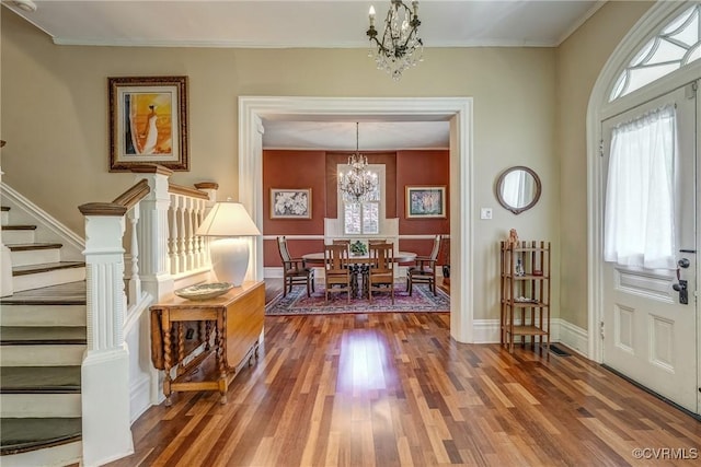 entryway with plenty of natural light, stairs, wood finished floors, and a chandelier