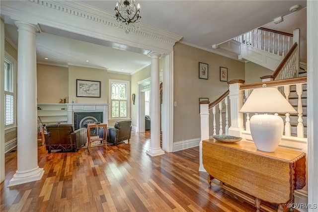 interior space featuring crown molding, decorative columns, stairs, and wood finished floors