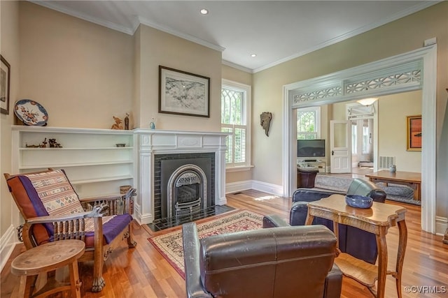 sitting room with crown molding, a fireplace with flush hearth, and wood finished floors