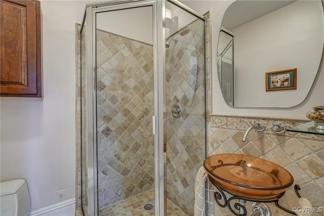 full bath featuring wainscoting, toilet, tile walls, and a shower stall