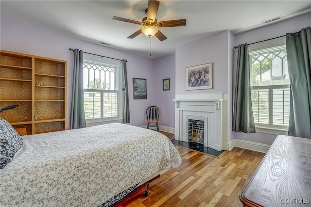 bedroom featuring visible vents, baseboards, a fireplace, and multiple windows
