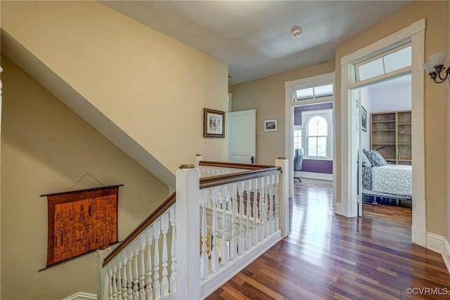 interior space featuring baseboards, an upstairs landing, and wood finished floors