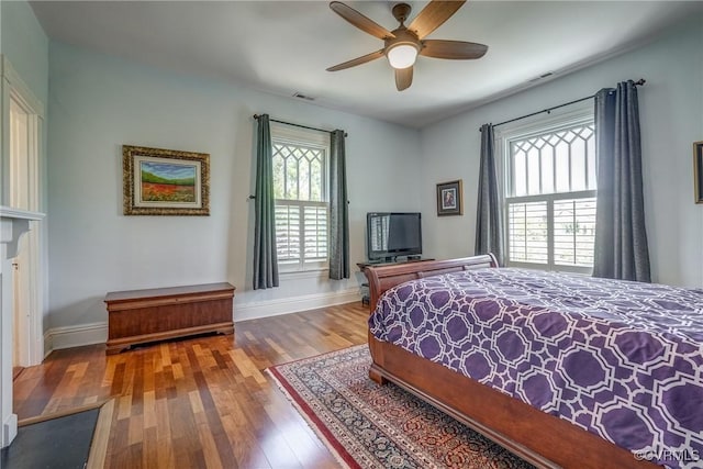 bedroom with baseboards, visible vents, multiple windows, and wood finished floors
