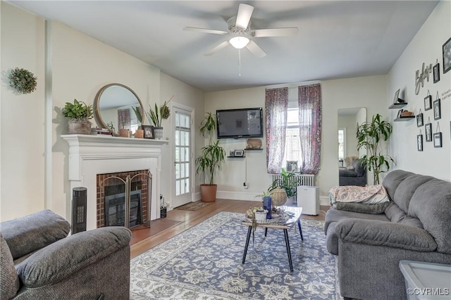 4821 W Seminary Ave, Richmond, VA 23227 - living room with a brick fireplace, a ceiling fan, wood finished floors, and baseboards