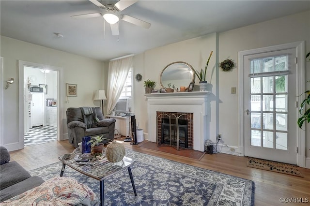 4821 W Seminary Ave, Richmond, VA 23227 - living room featuring a brick fireplace, a ceiling fan, and wood finished floors