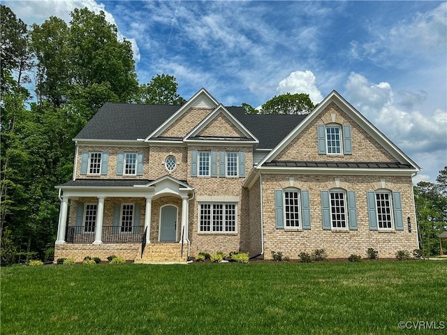 craftsman house with brick siding, a front yard, and covered porch