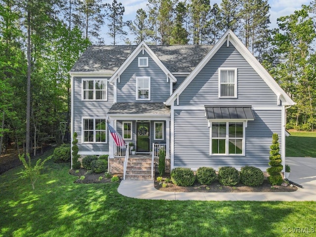 view of front of house with a standing seam roof, roof with shingles, metal roof, and a front yard