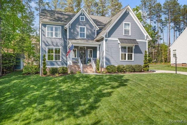 view of front of house with a shingled roof, a porch, and a front yard