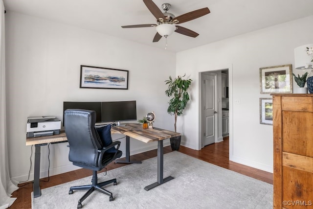 home office with a ceiling fan, baseboards, and wood finished floors