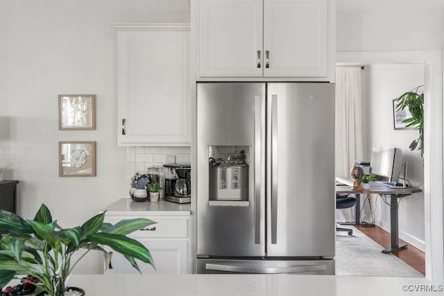 kitchen with tasteful backsplash, light countertops, stainless steel fridge, white cabinetry, and dark wood-type flooring