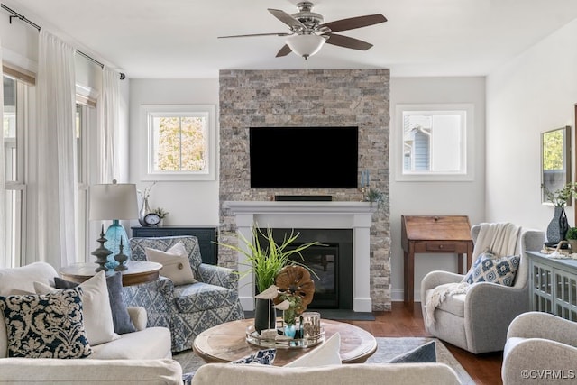 living area with a ceiling fan, wood finished floors, and a fireplace