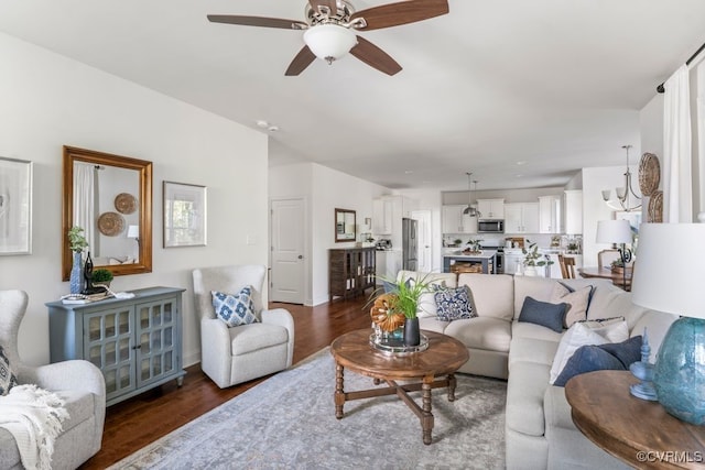 living room with a ceiling fan, baseboards, and dark wood-type flooring