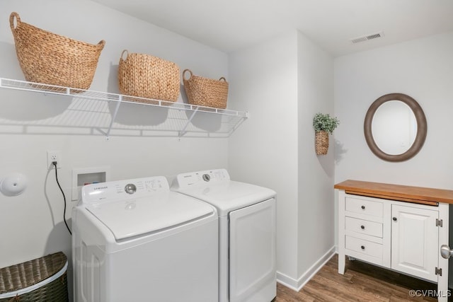 washroom with laundry area, visible vents, washing machine and dryer, wood finished floors, and baseboards