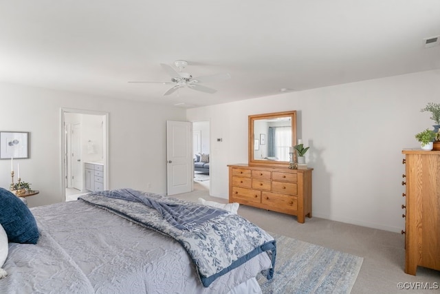 bedroom with ensuite bathroom, light carpet, a ceiling fan, and visible vents