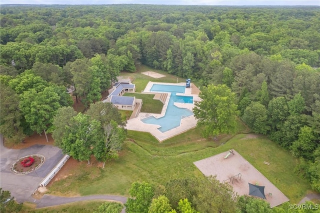 view of property location with a heavily wooded area and a pool area