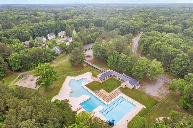 drone / aerial view of a heavily wooded area and a pool area