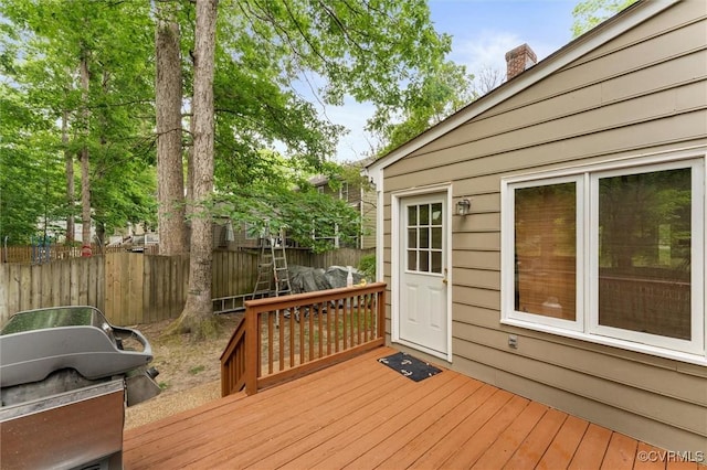 wooden terrace featuring fence and a grill