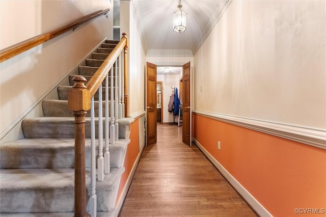 corridor with stairway, wood finished floors, crown molding, and baseboards