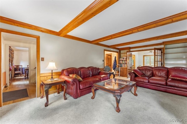carpeted living area featuring wainscoting, beamed ceiling, and crown molding