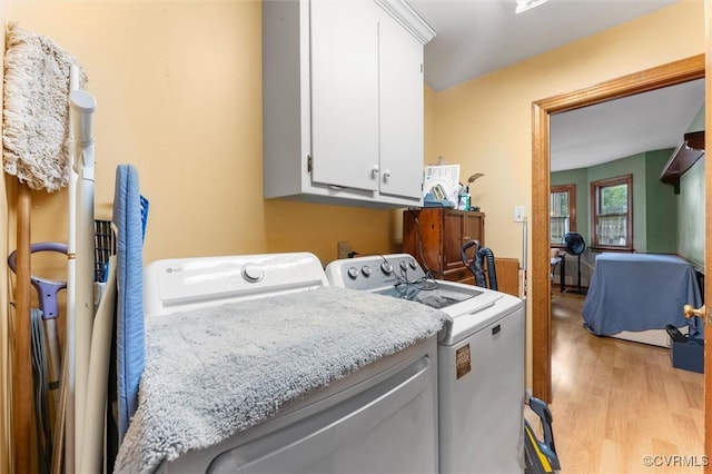 laundry room with separate washer and dryer, cabinet space, and light wood finished floors