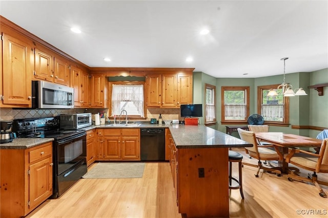 kitchen with black appliances, a sink, a peninsula, light wood finished floors, and recessed lighting