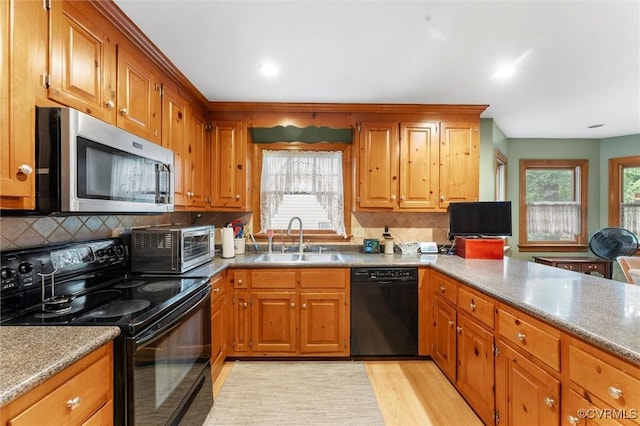 kitchen featuring black appliances, a sink, brown cabinetry, and recessed lighting