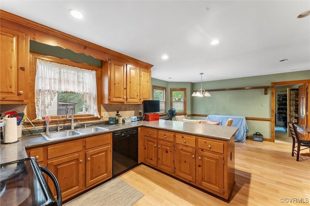 kitchen with a sink, black appliances, a peninsula, light wood-style floors, and brown cabinetry