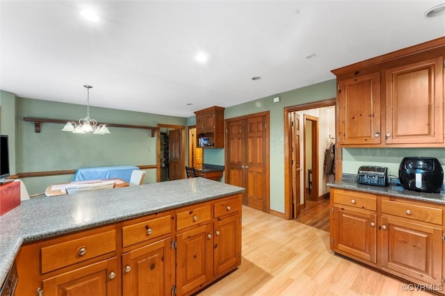 kitchen with brown cabinets, light wood finished floors, pendant lighting, a chandelier, and recessed lighting