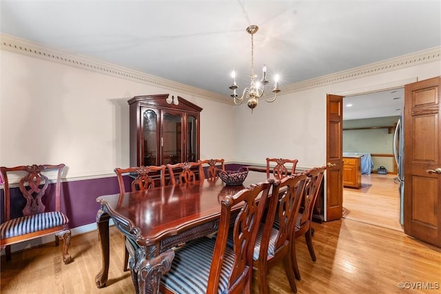 dining space featuring a chandelier, light wood finished floors, and crown molding