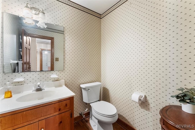 half bathroom featuring toilet, vanity, a chandelier, and wood finished floors