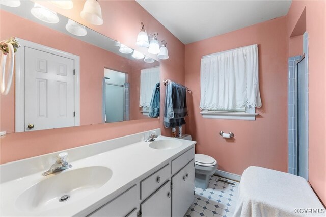 full bath featuring a shower with door, double vanity, toilet, baseboards, and tile patterned floors
