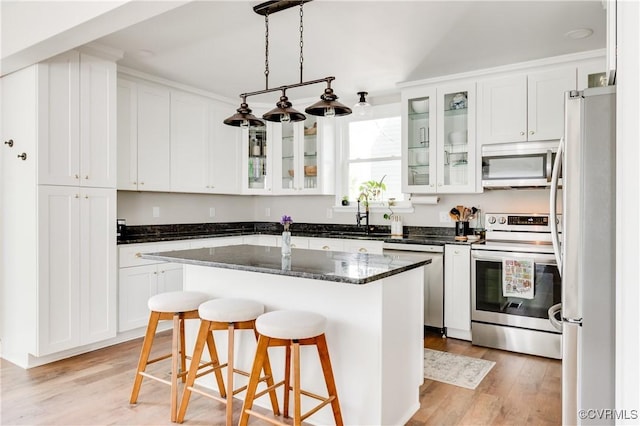 kitchen with white cabinetry, appliances with stainless steel finishes, a sink, and light wood-style floors