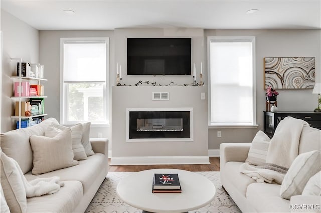 living area featuring visible vents, baseboards, wood finished floors, and a wealth of natural light