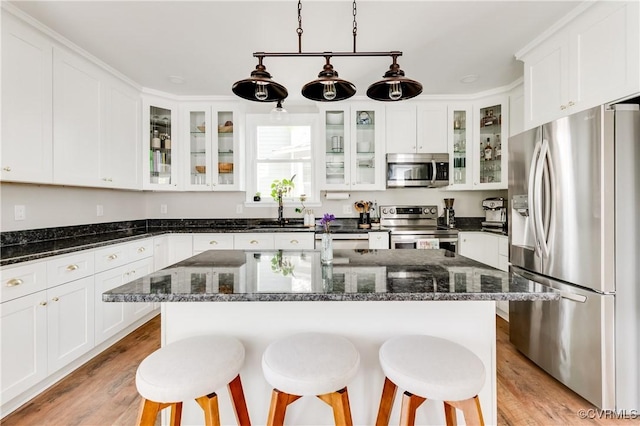 kitchen featuring a sink, appliances with stainless steel finishes, a kitchen breakfast bar, and white cabinetry