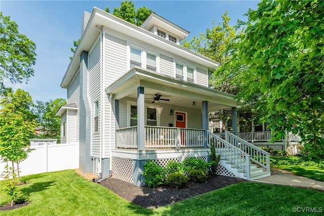 american foursquare style home featuring a porch, ceiling fan, fence, and a front yard