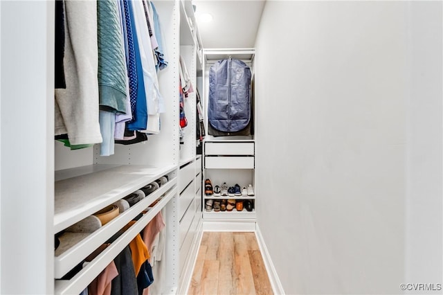 walk in closet with light wood finished floors
