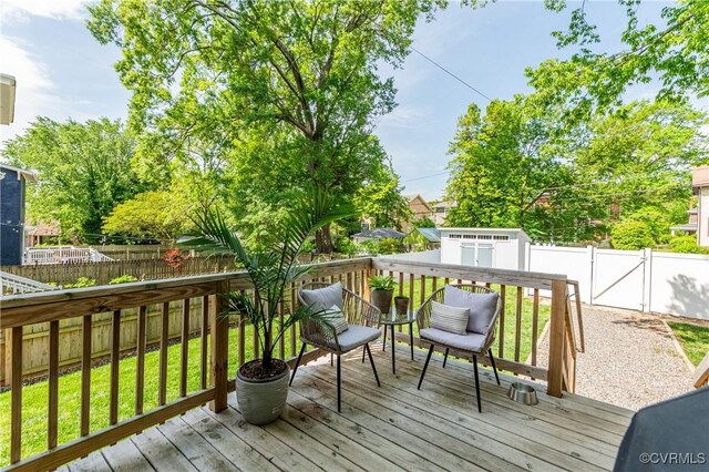 wooden terrace with a storage shed, a gate, an outbuilding, and a fenced backyard